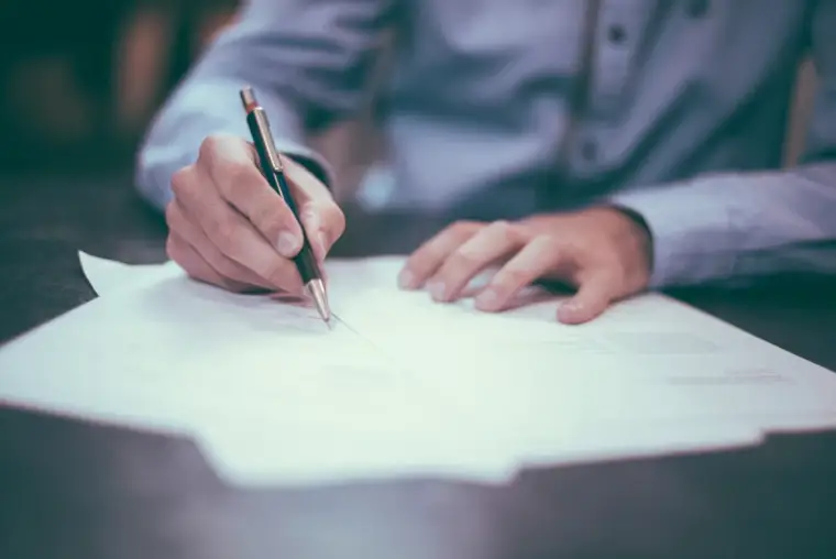 Close-up of a person signing a document with a pen